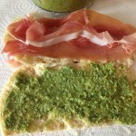 Layered pesto on one side 2 slices proscicutto and  fonitnella cheese on the other side
